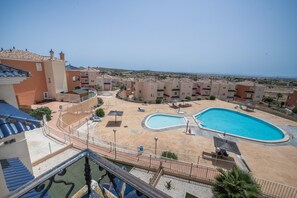 A residential area with a swimming pool, balconies, and a clear sky.