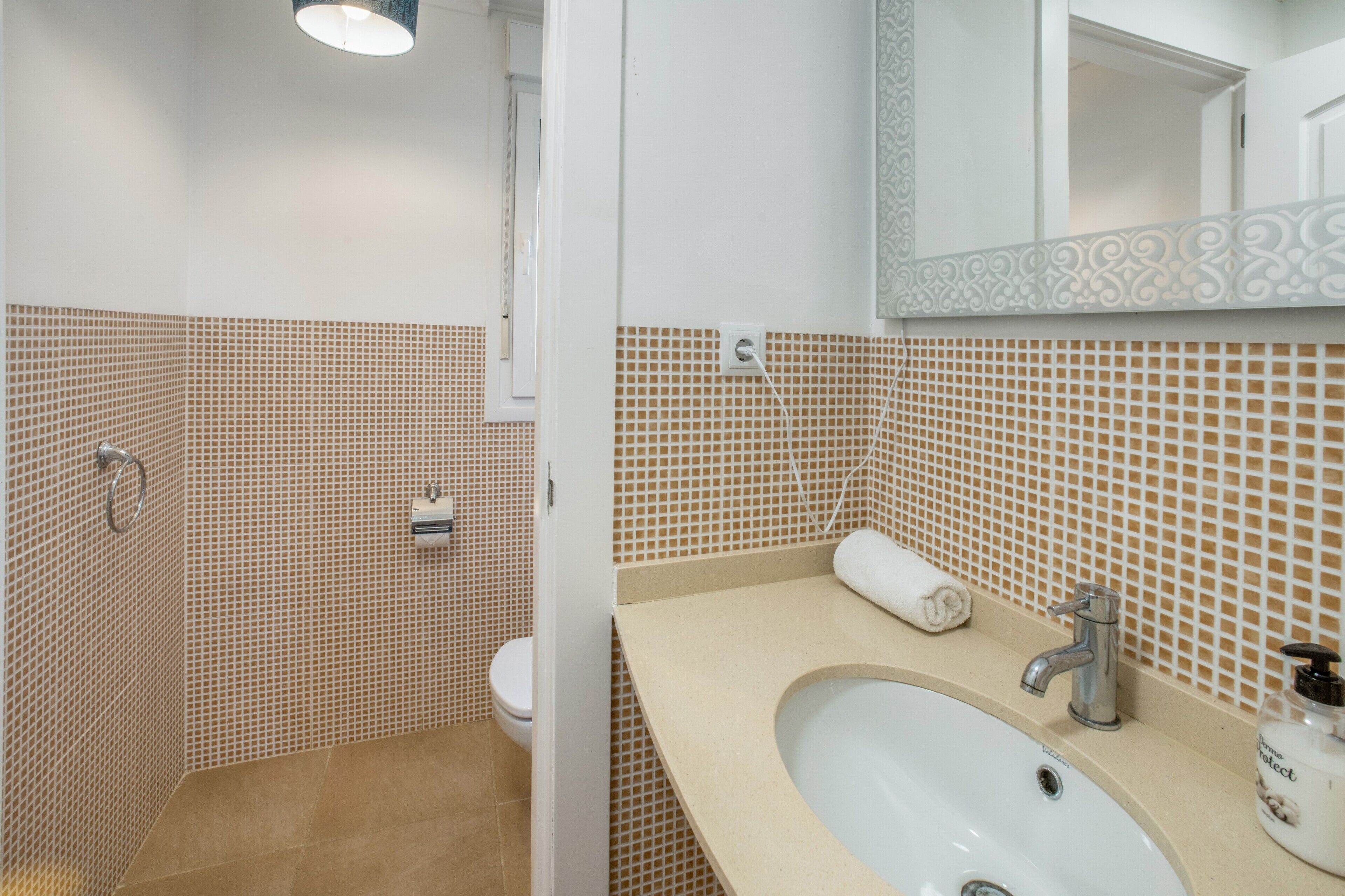 Un baño con lavamanos blanco, un espejo y un inodoro.