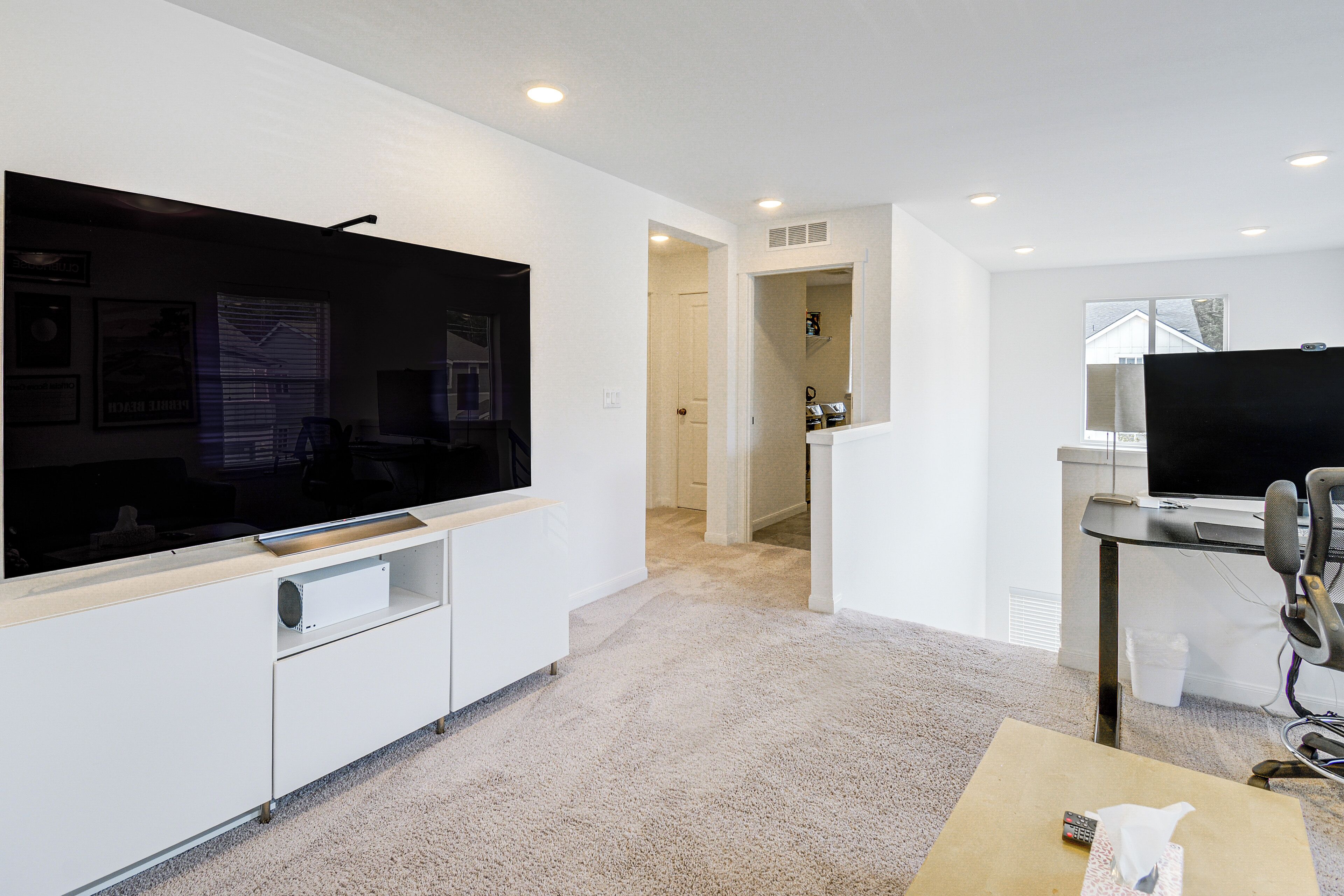 A modern living room with a flat-screen TV, a coffee table, and a desk with a computer.