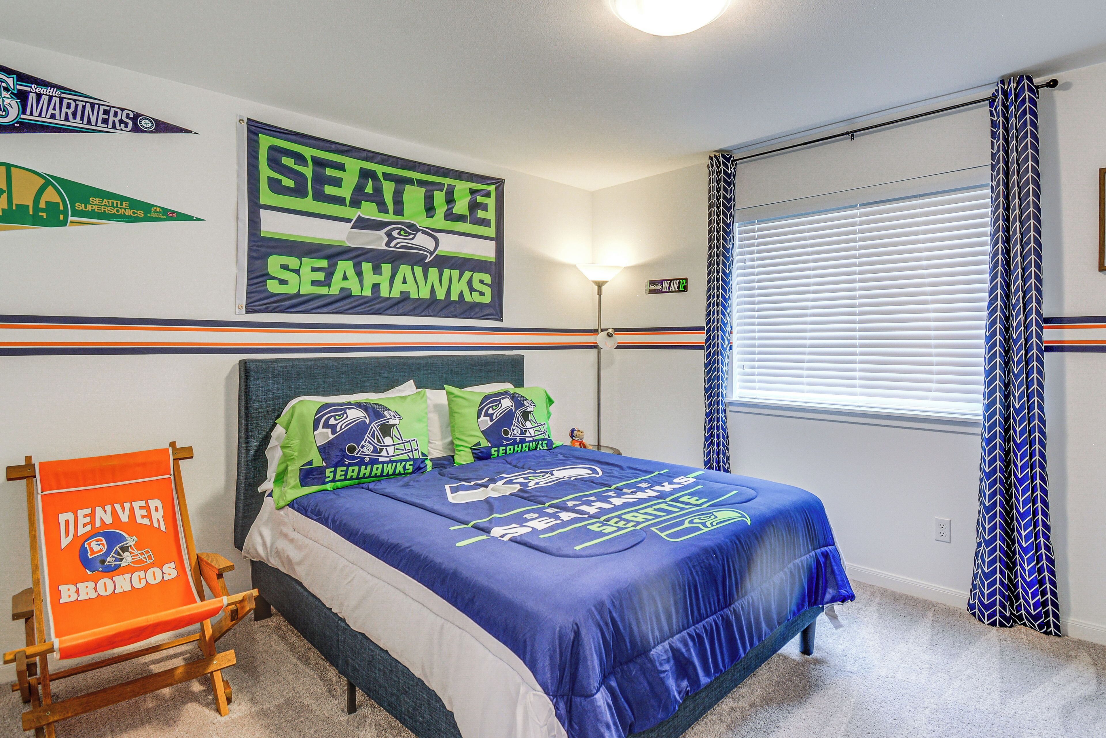 Une chambre d’hôtel avec un lit, une chaise et un mur décoré aux couleurs des Seahawks de Seattle et des Broncos de Denver.