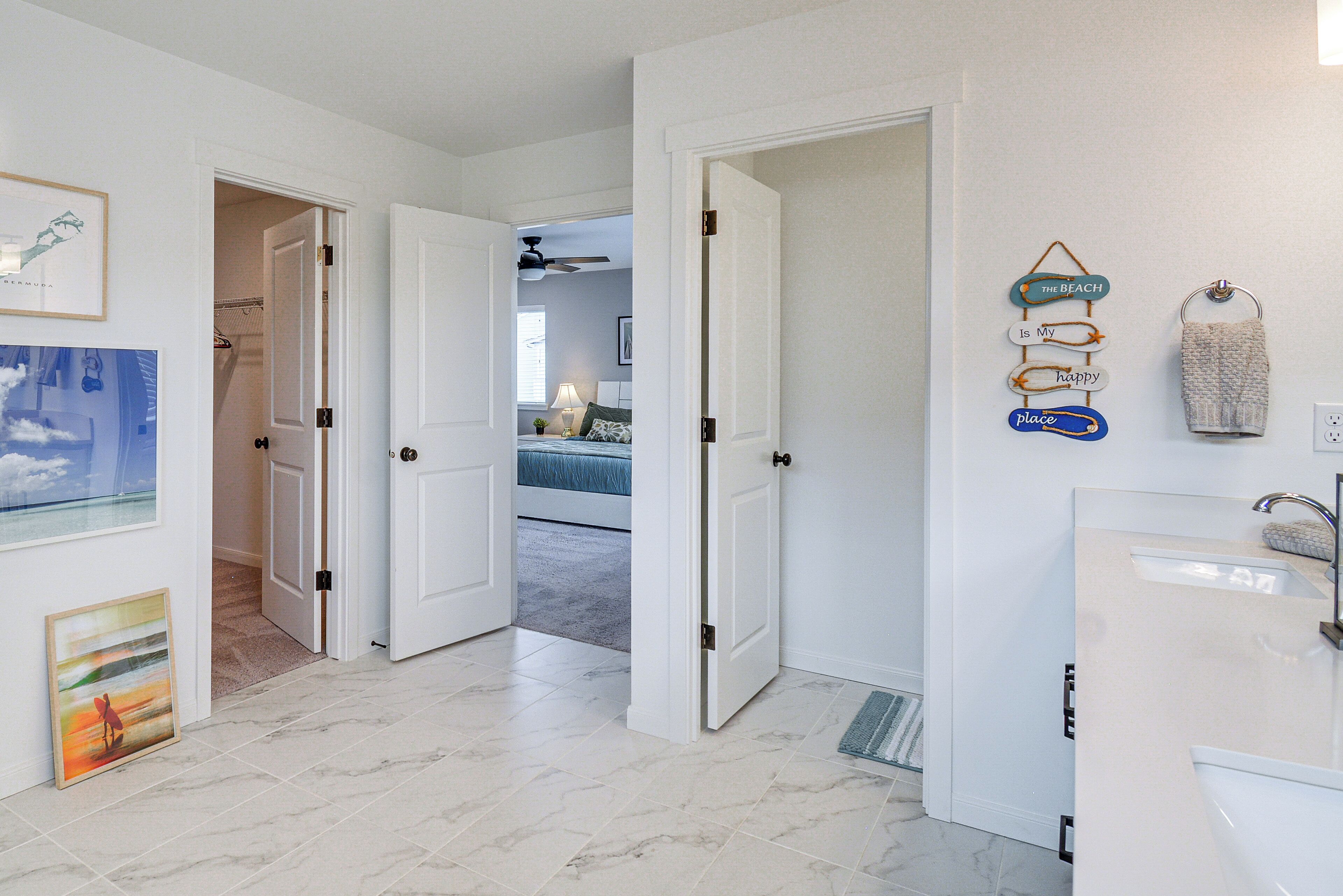 Een hotelkamer met badkamer, een gang naar een slaapkamer, en uitzicht op het strand.