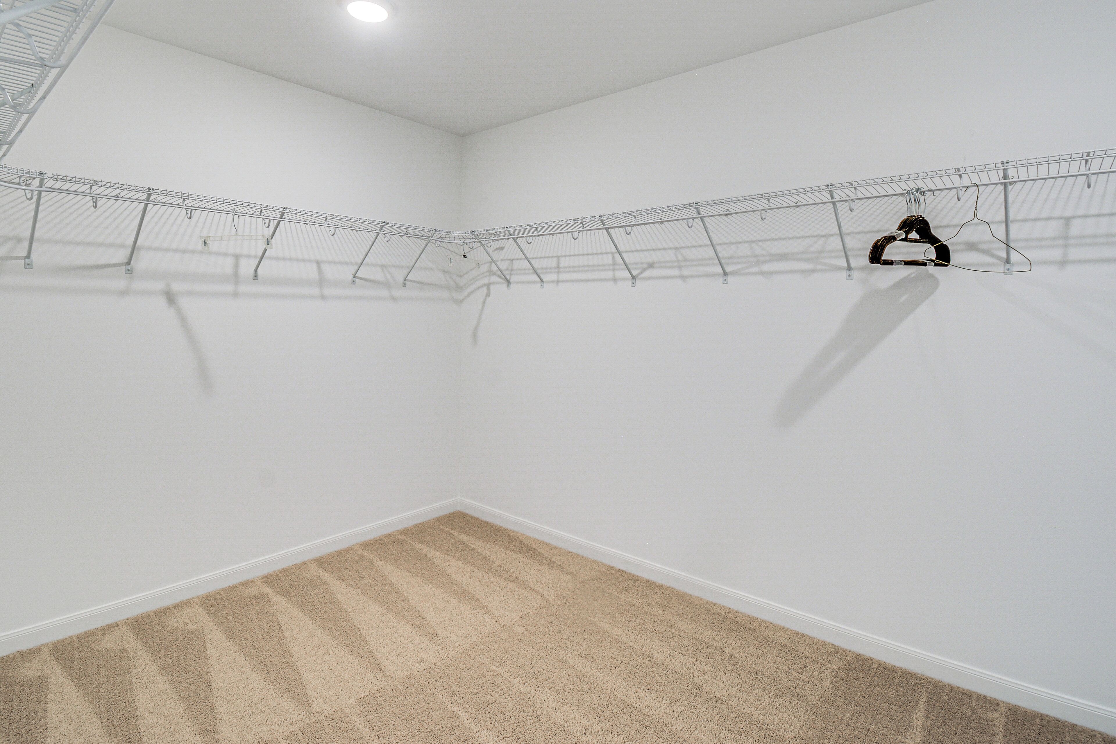 Une pièce d’angle dotée d’un sol recouvert de moquette, de murs blancs et d’un étendoir à linge en métal.