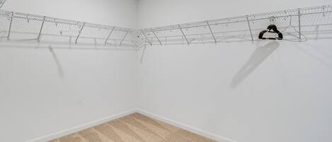 Une pièce d’angle dotée d’un sol recouvert de moquette, de murs blancs et d’un étendoir à linge en métal.