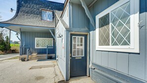 A blue building with a dark entrance door, a covered porch, and a window with a diamond pattern. - Explore Port Huron! Cozy Condo w/ Creek Views (Port Huron)