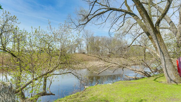 A serene lakeside scene with trees, a grassy area, and a clear sky. - Explore Port Huron! Cozy Condo w/ Creek Views (Port Huron)