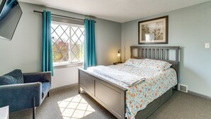A bedroom with a bed, a nightstand, a chair, a window with curtains, and a wall-mounted picture. - Explore Port Huron! Cozy Condo w/ Creek Views (Port Huron)