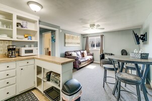 Un espacio habitable compacto con kitchenette, zona de comedor y sala de estar con sofá y sillones.