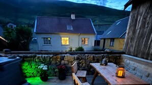 A wooden deck with a table and benches, a hot tub, and a stone wall. - Hvanngarðs Smáttan við Stórá (Dalur)