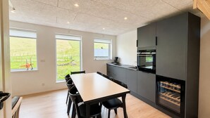A modern kitchen with a dining table, chairs, and a built-in wine cooler. - Hvanngarðs Smáttan við Stórá (Dalur)