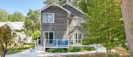 A two-story house with a porch, a small garden, and a picnic table.