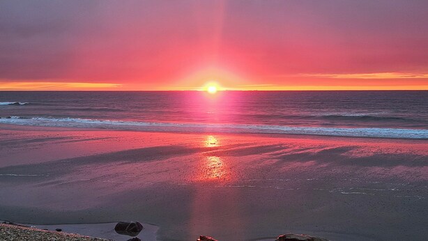 A sunset over a beach with waves, rocks, and a clear sky. - Coastal Hampton Condo: Walk to North Beach! (Hampton)