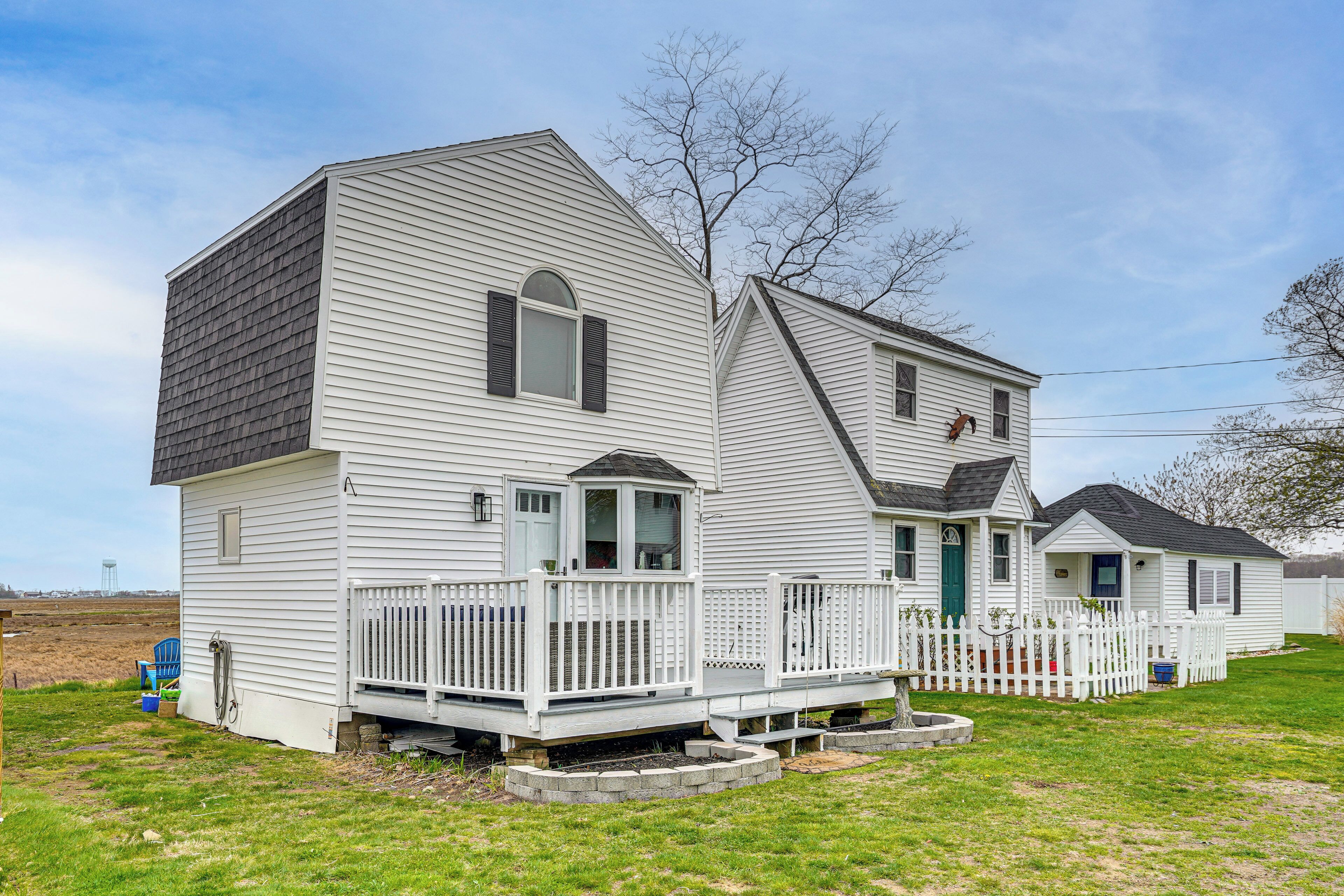 A two-story house with a front porch, a small deck, and a fenced yard.