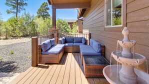 Une terrasse en bois avec un canapé modulable intégré et une fontaine en pierre.