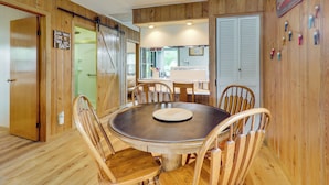 A wooden interior with a round dining table, wooden chairs, a kitchen area, and a sign that reads 'Good times come to those who bait.' - Lake Webster Retreat: Pier, Kayaks & Fire Pit (North Webster)