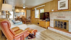 A cozy living room with a fireplace, leather furniture, and a television. - Lake Webster Retreat: Pier, Kayaks & Fire Pit (North Webster)