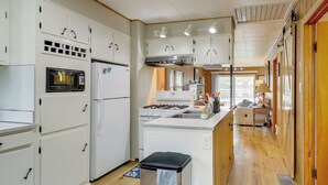 A kitchen with white cabinets, a stove, and a sink. - Lake Webster Retreat: Pier, Kayaks & Fire Pit (North Webster)