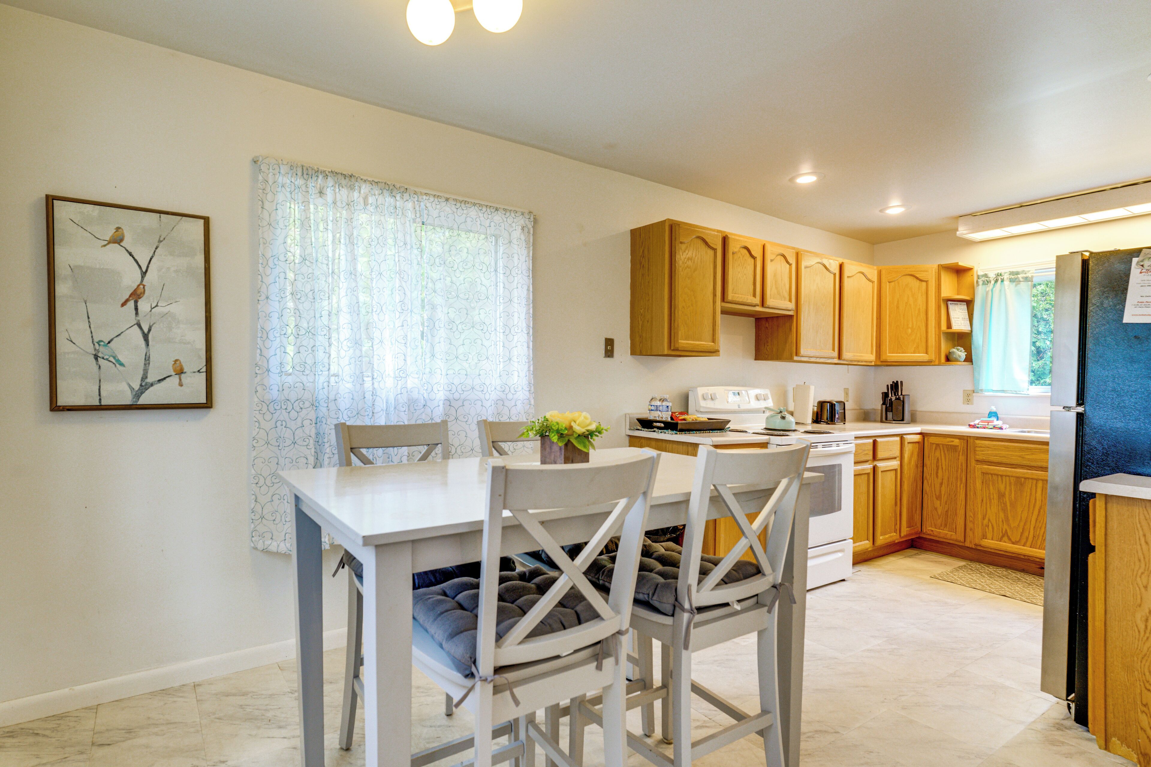 A modern kitchen with wooden cabinets, a white dining table, and a refrigerator.