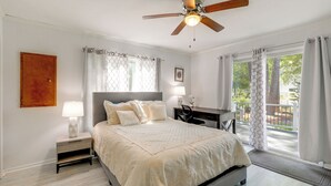 Une chambre à coucher comprenant un lit, une table de chevet, un bureau et donnant sur l’extérieur.