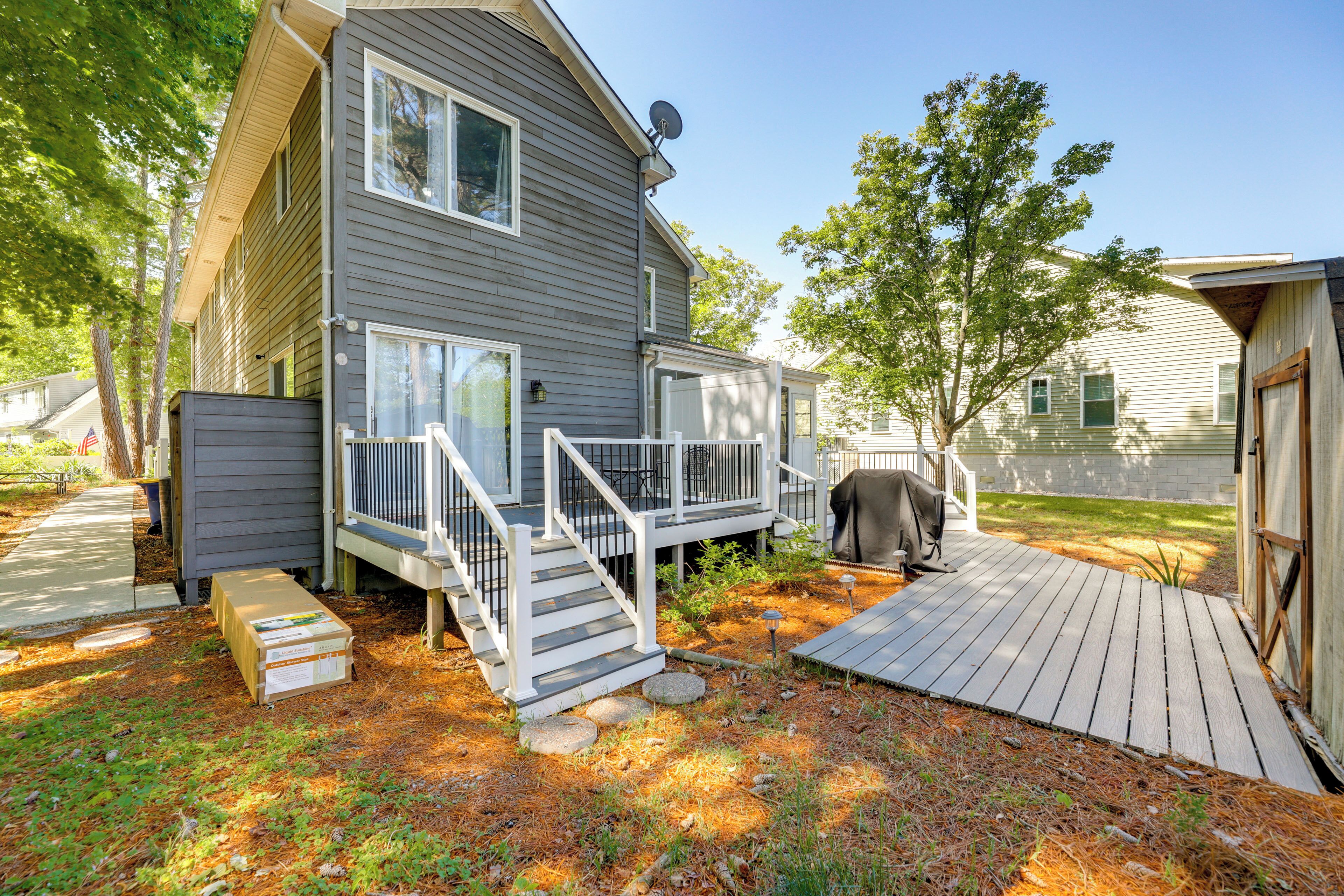 A two-story house with a deck, a satellite dish, and a covered outdoor area.