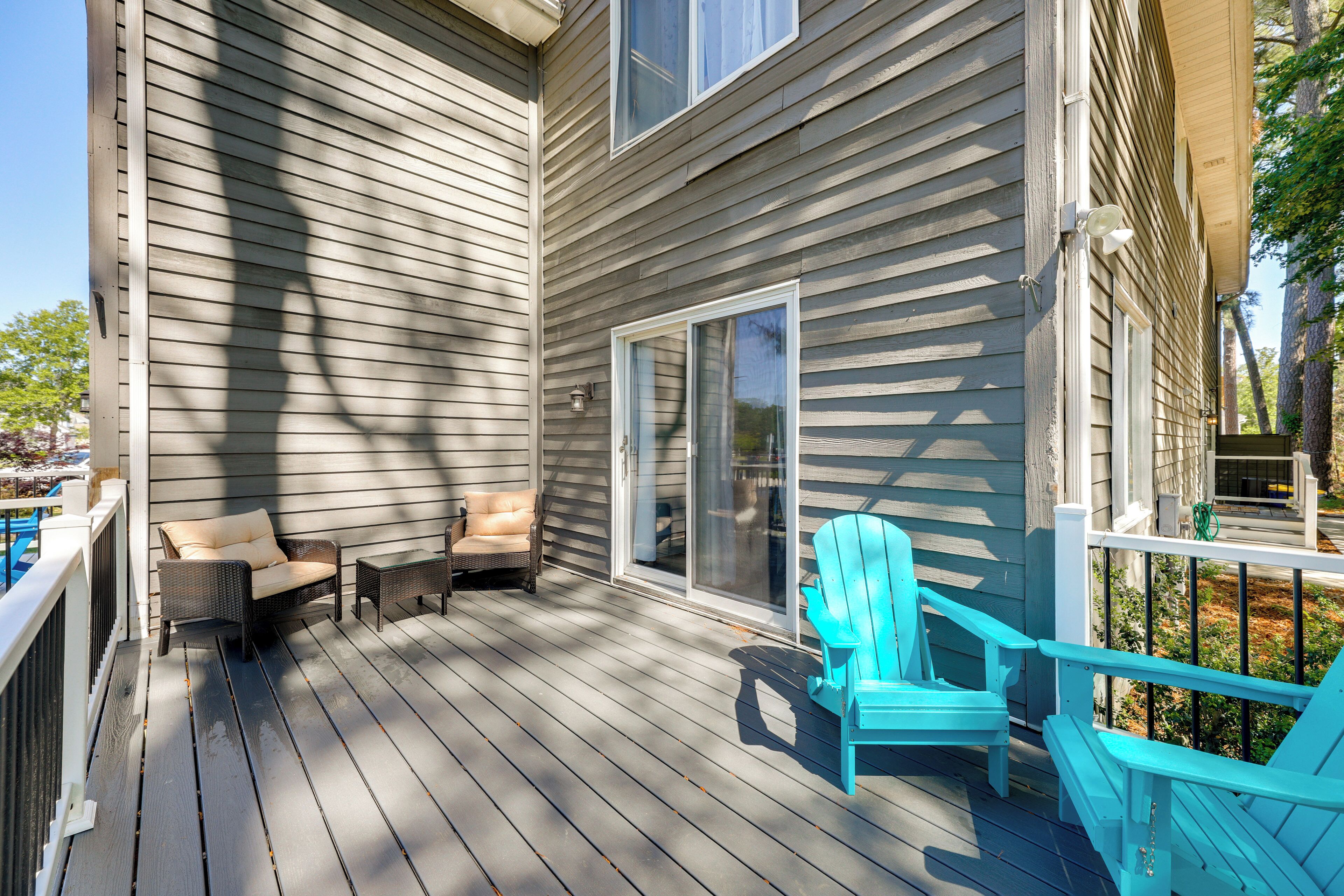 A covered deck with outdoor furniture, a sliding glass door, and a view of the surrounding area.