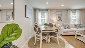 A living room with a round dining table, white sofas, and a large green plant. - Pool Time & Island Vibes! Hilton Head Getaway (Hilton Head Island)