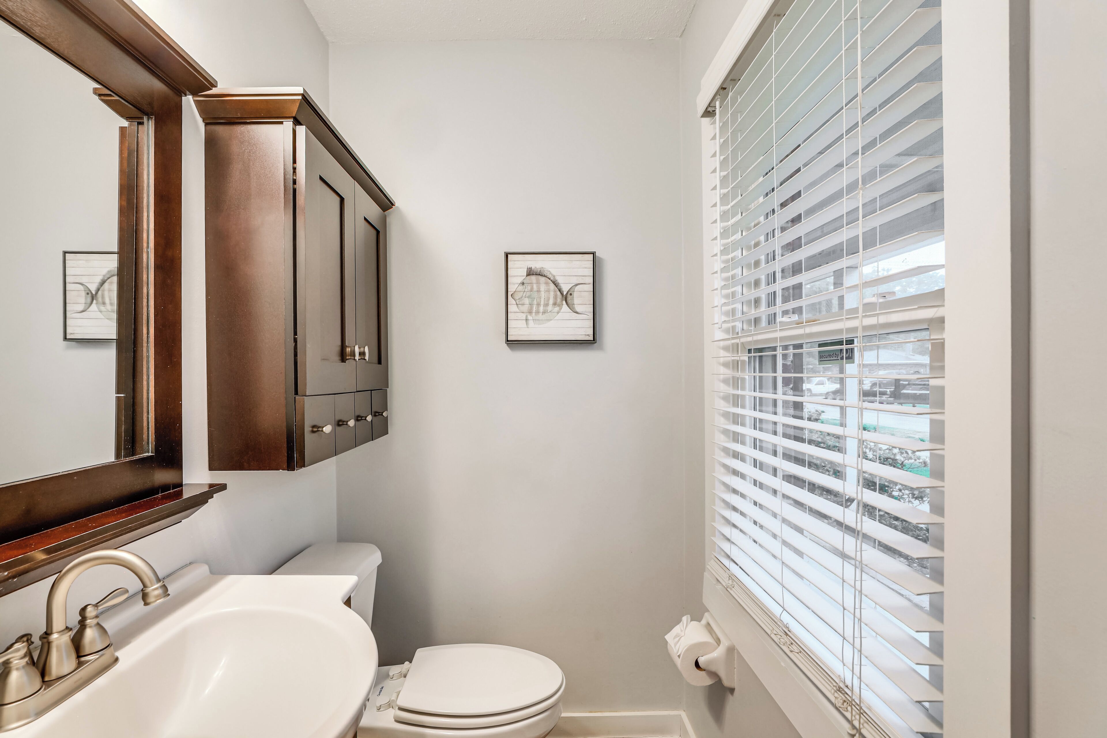 A bathroom with a sink, toilet, and window with blinds.