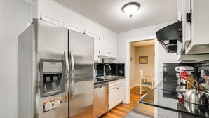 A modern kitchen with stainless steel appliances, a dishwasher, and a glass-top dining table.