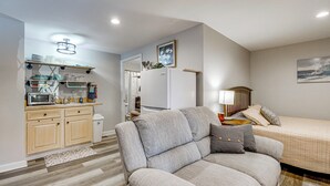 Uma sala moderna com sofá, cama, cozinha equipada e mesa de jantar.