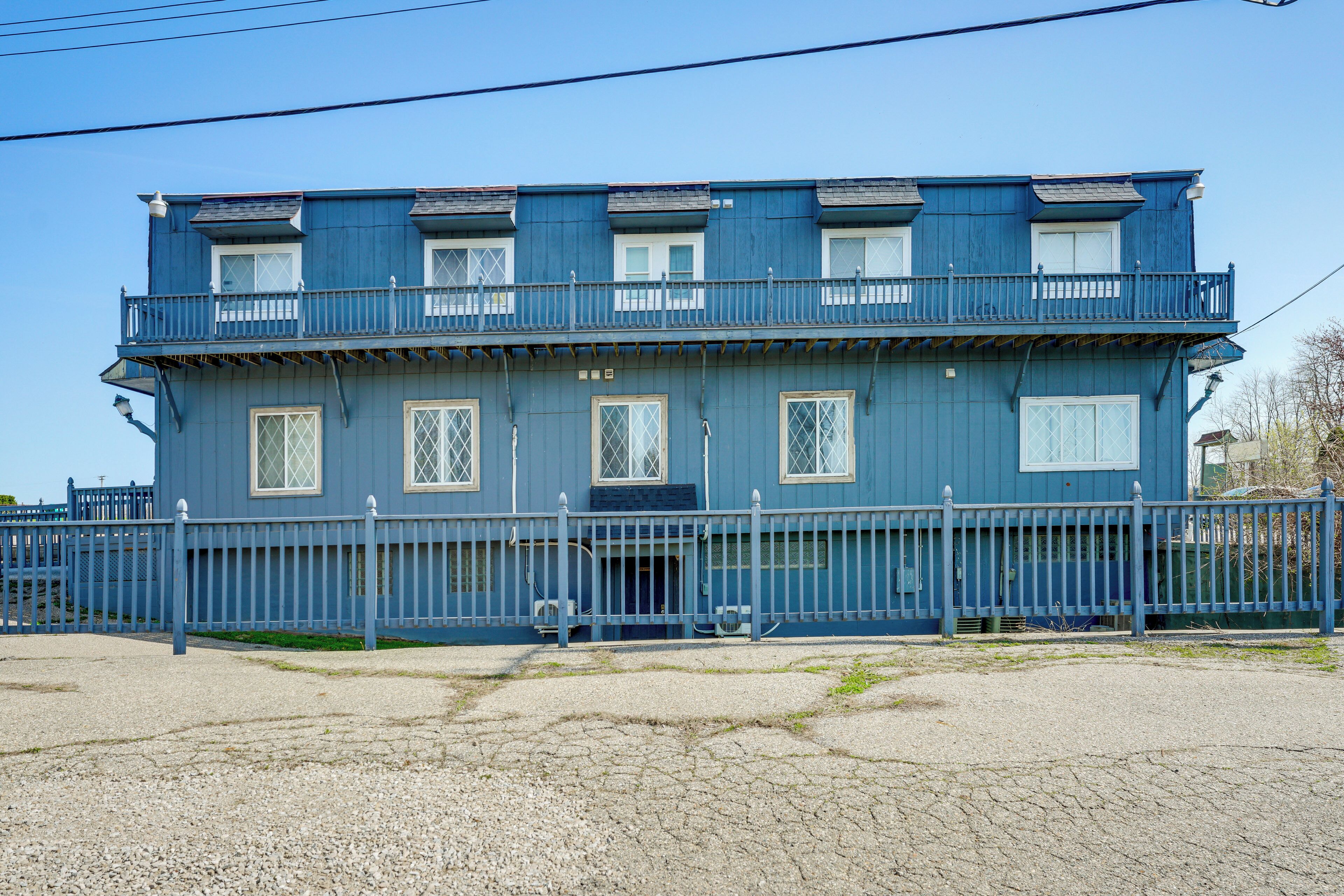 A two-story building with a balcony on the upper floor, a gated entrance, and a gravel driveway.