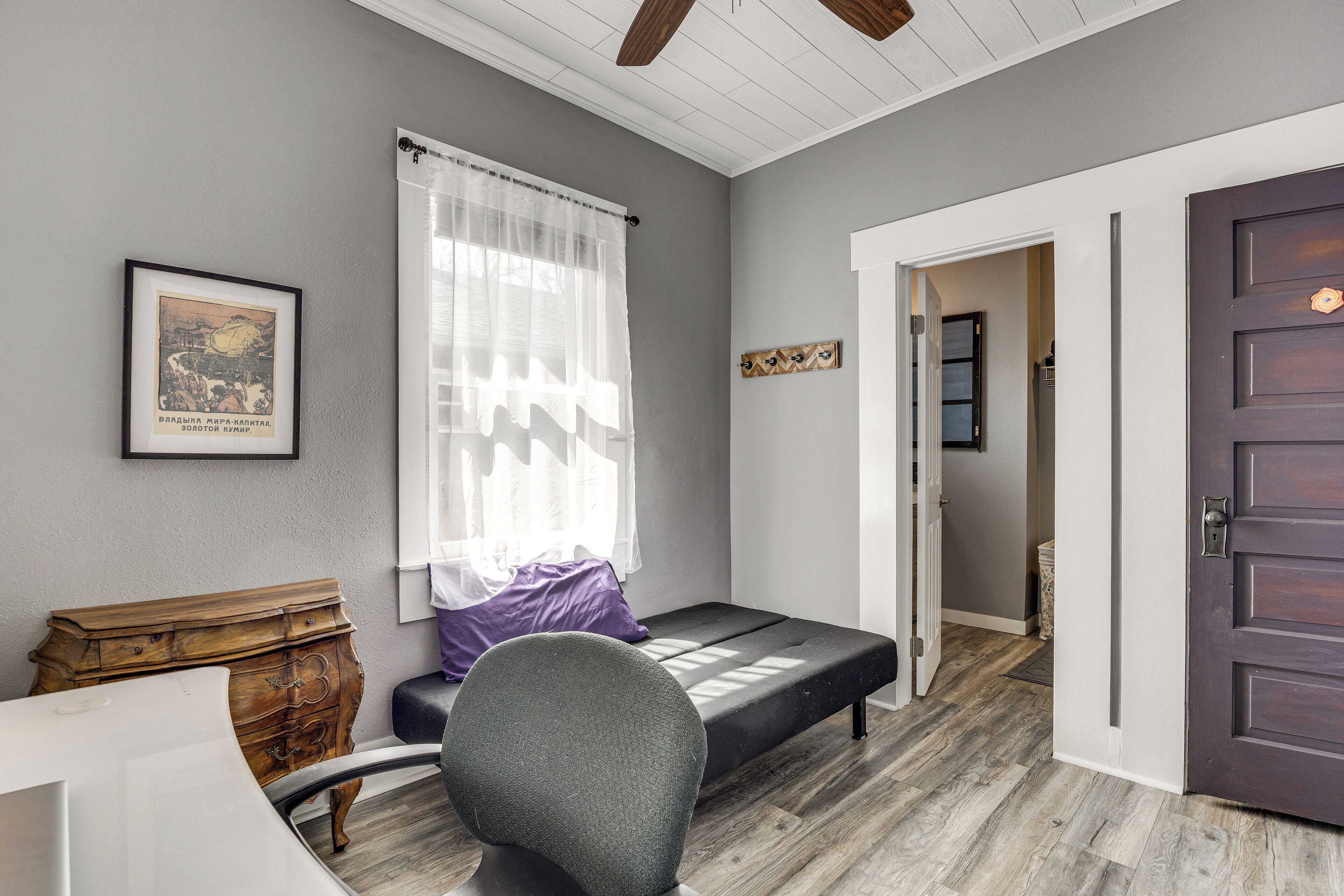 A room with a bed, a wooden dresser, a chair, a framed picture on the wall, and a door.