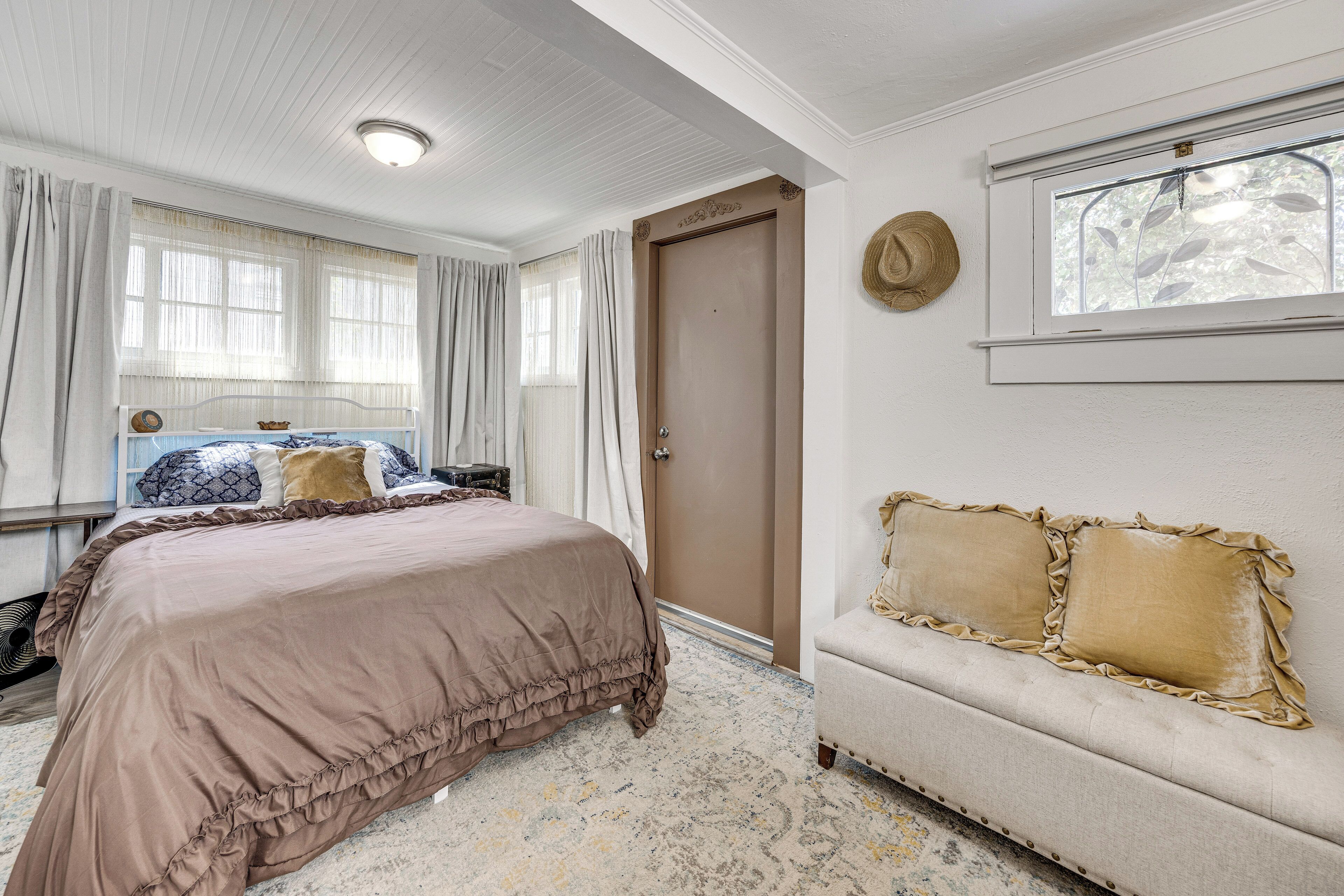 A bedroom with a bed, a sofa, a window, and a door.