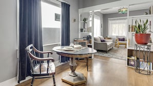 Uma sala de estar com uma mesa de jantar, um sofá e uma estante de livros.