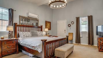 Ein Schlafzimmer mit einem hölzernen Bett, Nachttischen, einer Bank, einem TV-Schrank und einer Chandelier.