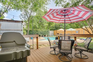 A wooden deck with a grill, a table with chairs, and a large striped umbrella. - 5 Mi to Will Rogers Center! Private Oasis w/ Grill (Fort Worth)