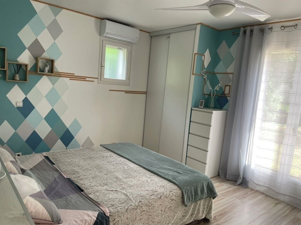 Une chambre à coucher avec un lit, une armoire, une fenêtre et un ventilateur de plafond.