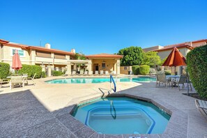 A swimming pool area with lounge chairs and umbrellas, surrounded by buildings with a tiled roof. - Community Perks! Modern PHX Condo: Extended Stay! (Phoenix)