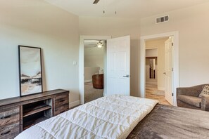A bedroom with a bed, a dresser, a chair, and a door leading to another room. - Community Perks! Modern PHX Condo: Extended Stay! (Phoenix)