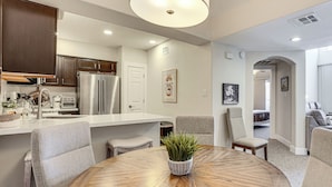 Una cocina moderna con electrodomésticos integrados, un comedor con mesa redonda y una sala de estar con sofá y sillones.
