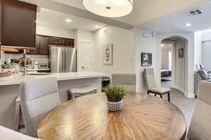 A modern kitchen with built-in appliances, a dining area with a round table, and a living space with a sofa and chairs. - Community Perks! Modern PHX Condo: Extended Stay! (Phoenix)