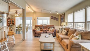 A spacious living room with a brown leather sofa, a wooden coffee table, and a dining area with wooden chairs and a cabinet. - < 1 Mi to Sand! Family-friendly Surfside Beach Gem (Murrells Inlet)