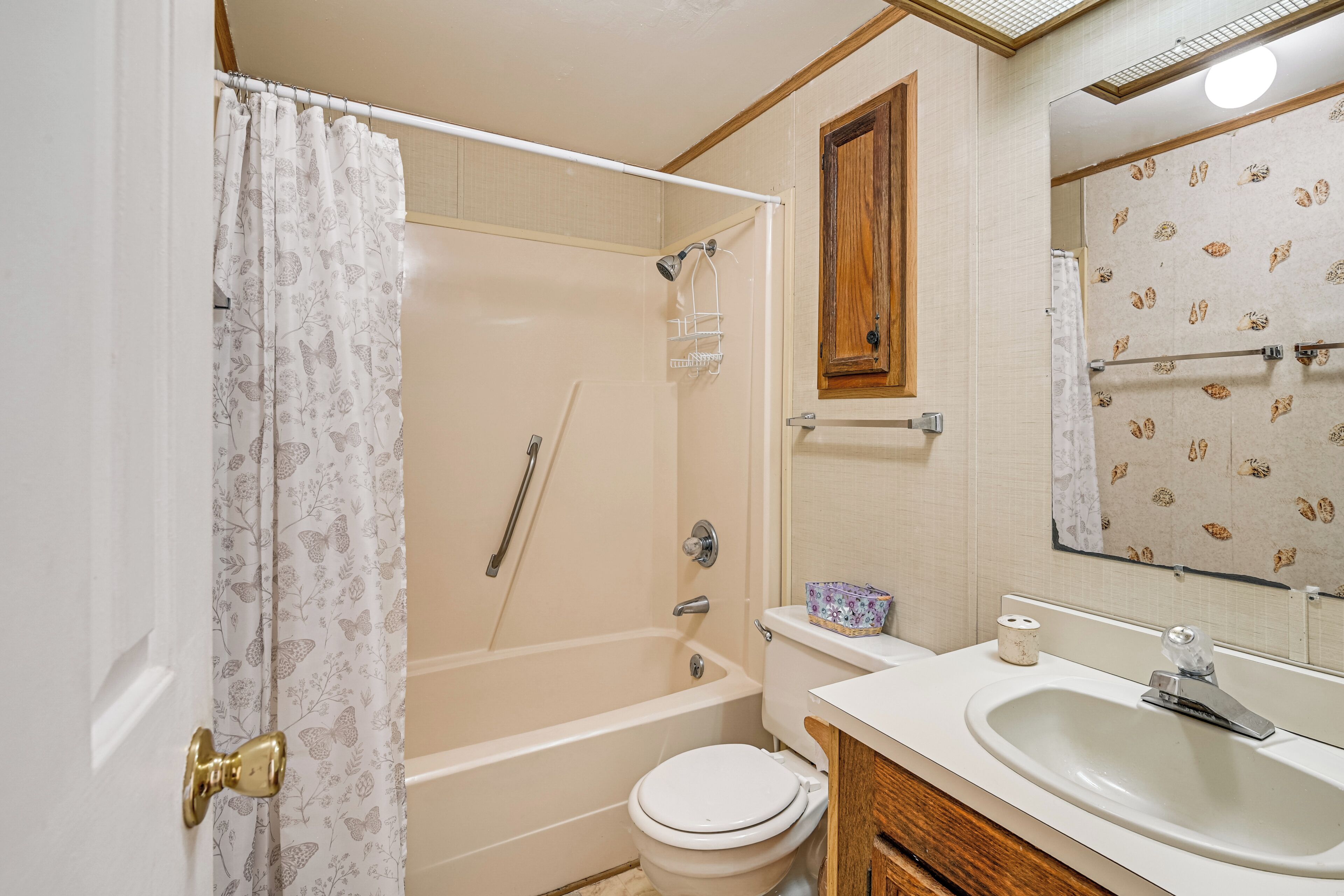 A bathroom with a bathtub, toilet, sink, and a mirror.