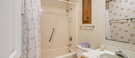 A bathroom with a bathtub, toilet, sink, and a mirror.