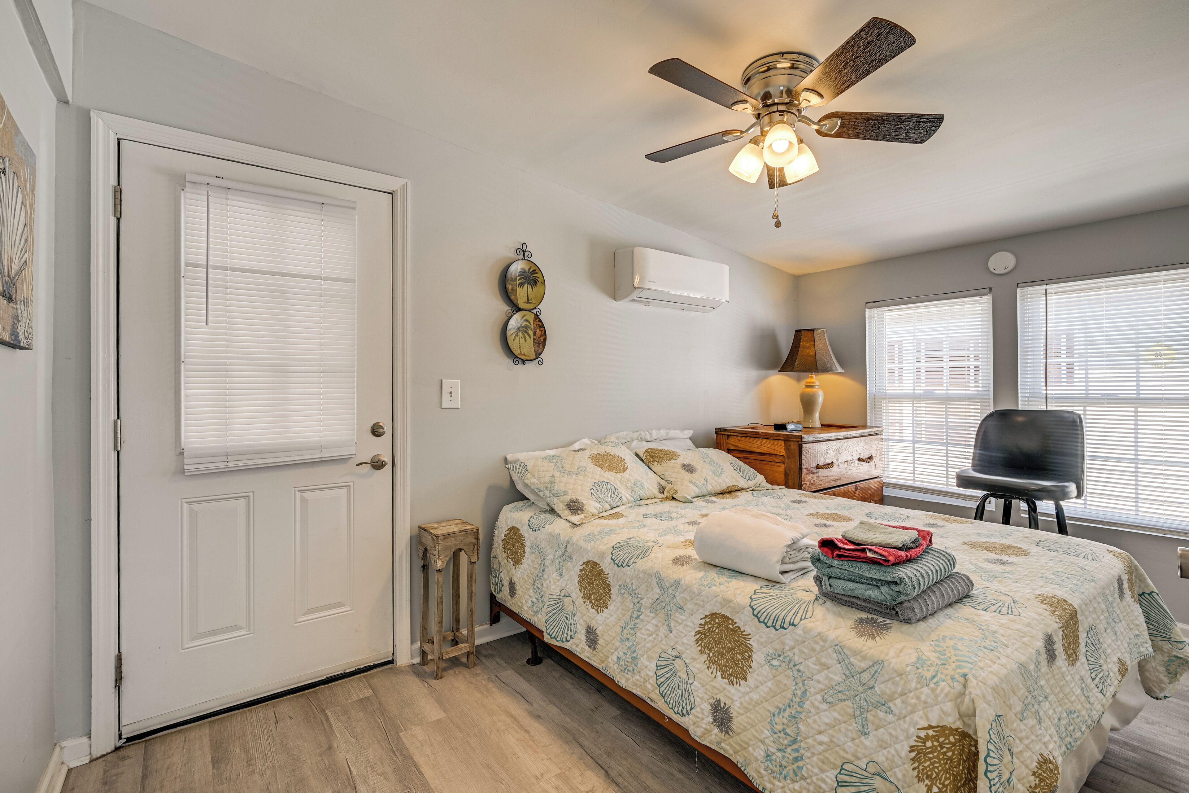 A bedroom with a bed, a ceiling fan, a nightstand, a lamp, and a chair.