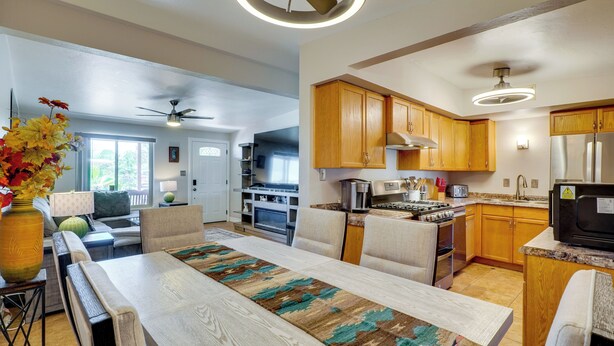 A modern kitchen with wooden cabinets, a stainless steel refrigerator, and a dining area with a table and chairs. - Outdoor Sanctuary + Gym! Retreat 4 Mi to Reid Park (Tucson)