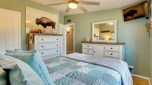 A bedroom with a bed, dresser, ceiling fan, and a mounted television. - Outdoor Sanctuary + Gym! Retreat 4 Mi to Reid Park (Tucson)
