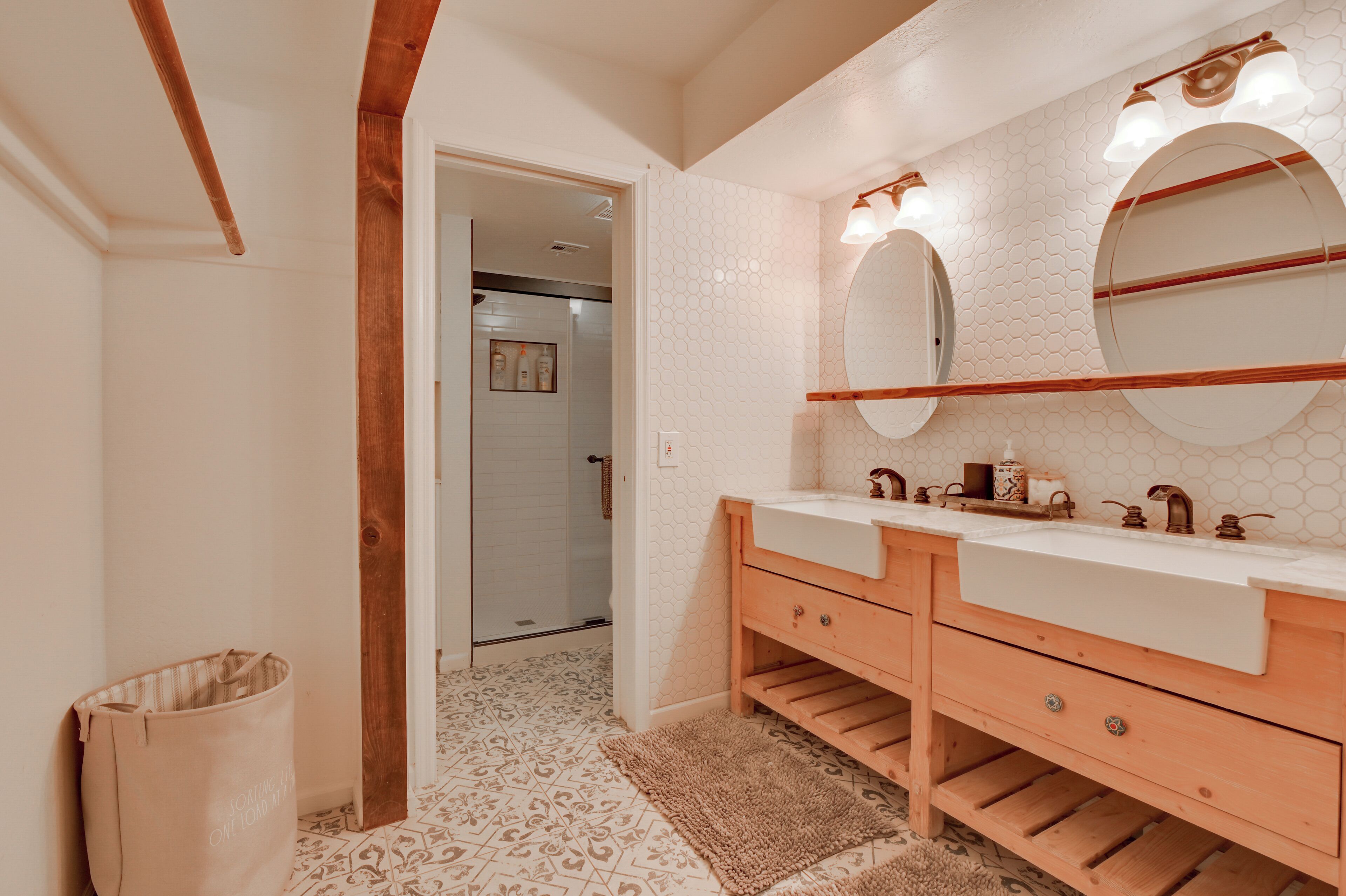 A bathroom with a double sink vanity, a large mirror, and a wooden door.