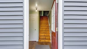 A staircase leading to a door with a red frame, a white door, and a gray mat at the bottom. - Near Trails & Lakes! Pemigewasset River Townhome (Franklin)