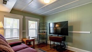 A room with a bed, a television on a stand, a small table, and a window with blinds. - Near Trails & Lakes! Pemigewasset River Townhome (Franklin)