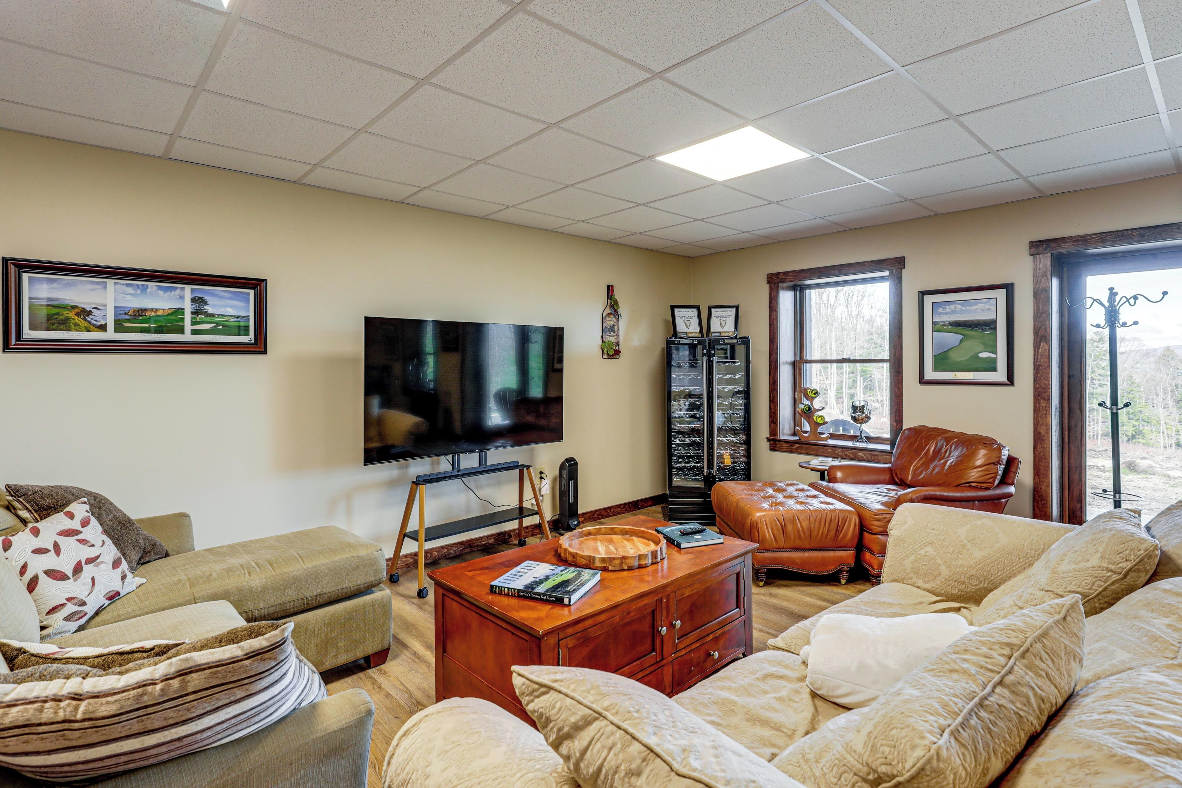 A living room with a television, leather sofas, a coffee table, and framed pictures on the walls.