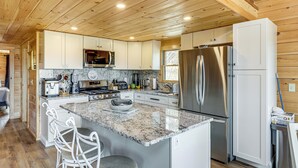 A modern kitchen with granite countertops, stainless steel appliances, and white cabinetry. - Newfound Lake Getaway: Cabin w/ Deck, Fire Pit (Bristol)